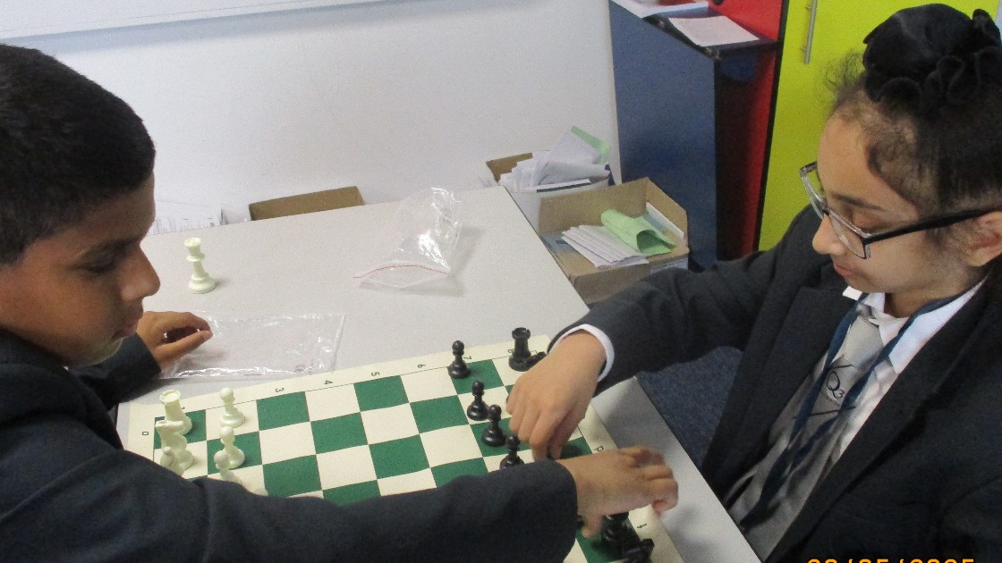 Two students playing chess at a table