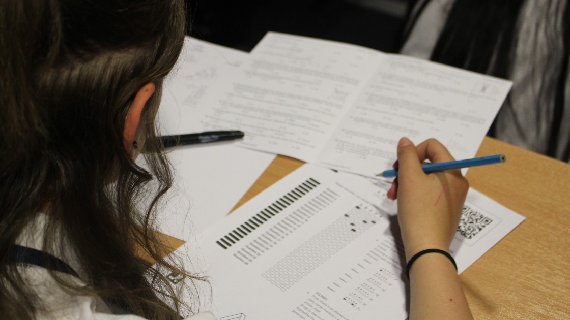 Student working on a maths challenge paper at a desk