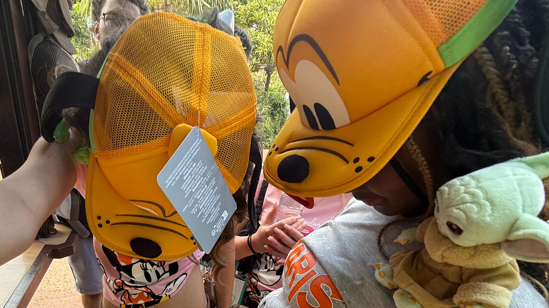 Two students wearing Pluto hats and a Yoda plush toy, standing close together