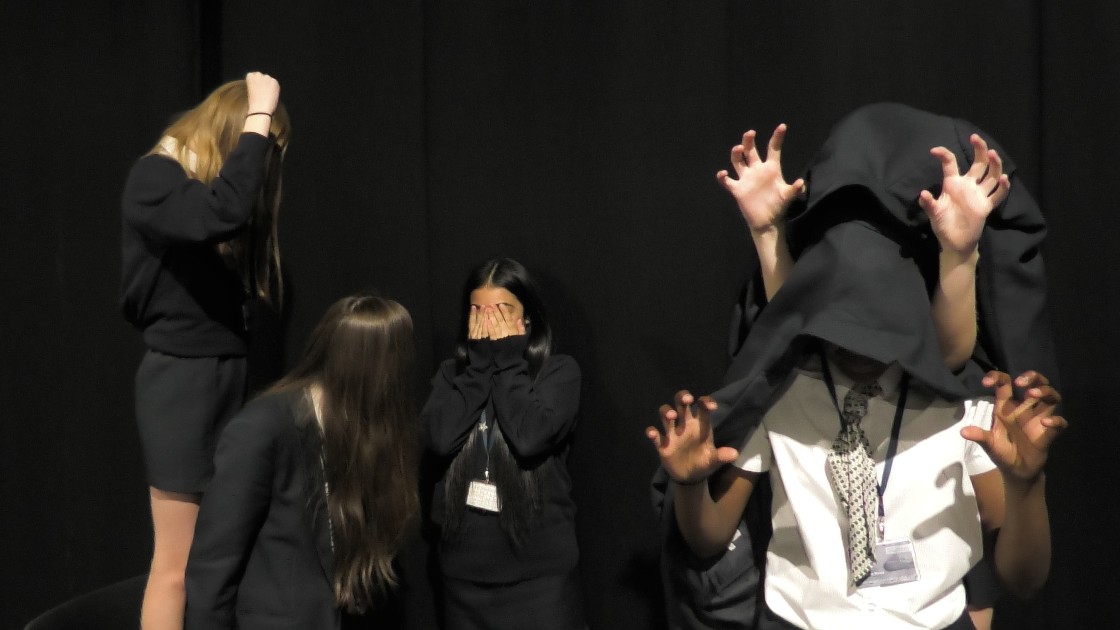 Students acting out a scene in a drama lesson, with expressive poses and gestures