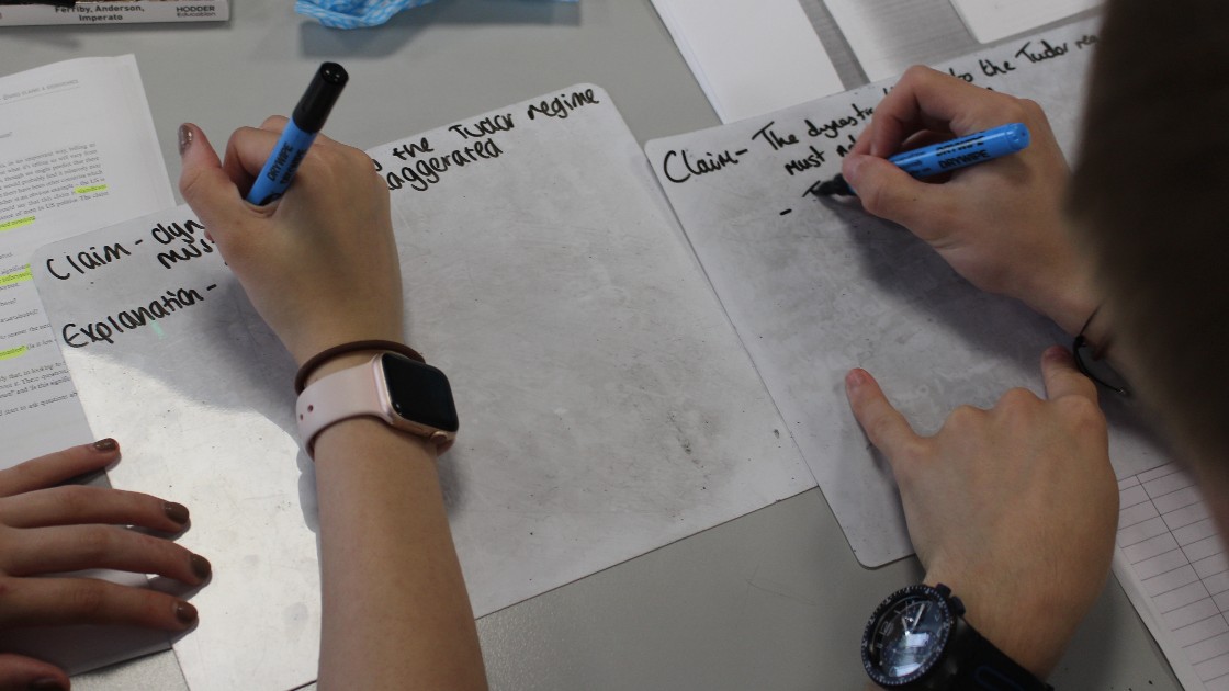 Students writing claims on whiteboards during a lesson