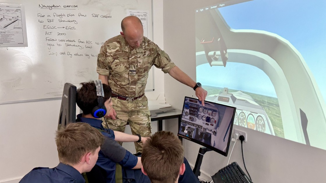 Teacher in military uniform instructing students using a flight simulator in a classroom
