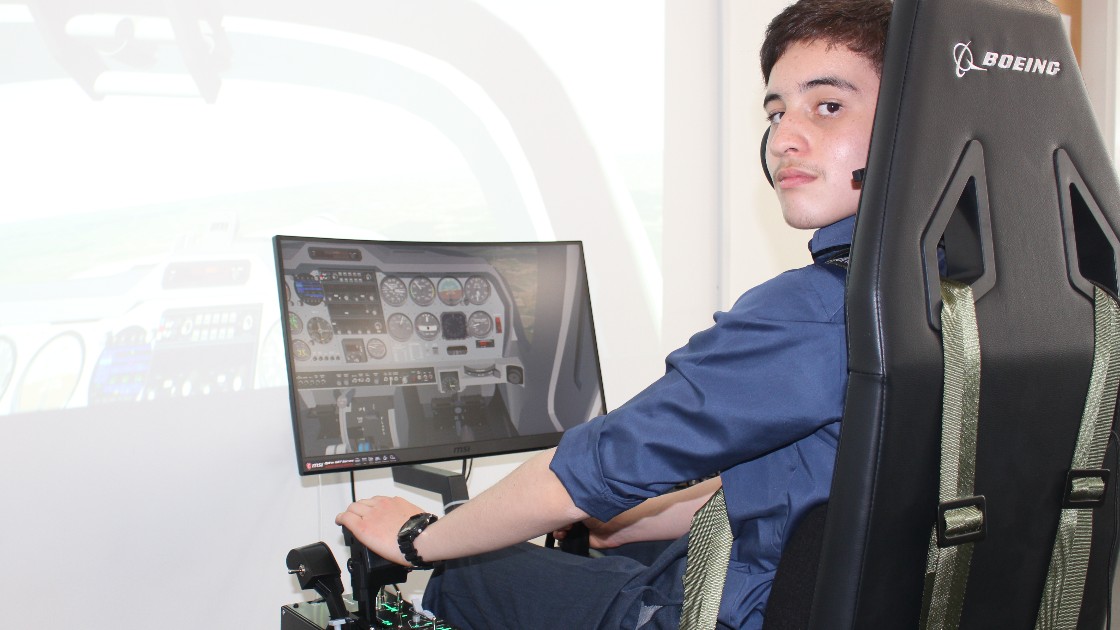 Student using a flight simulator with a Boeing seat and headset