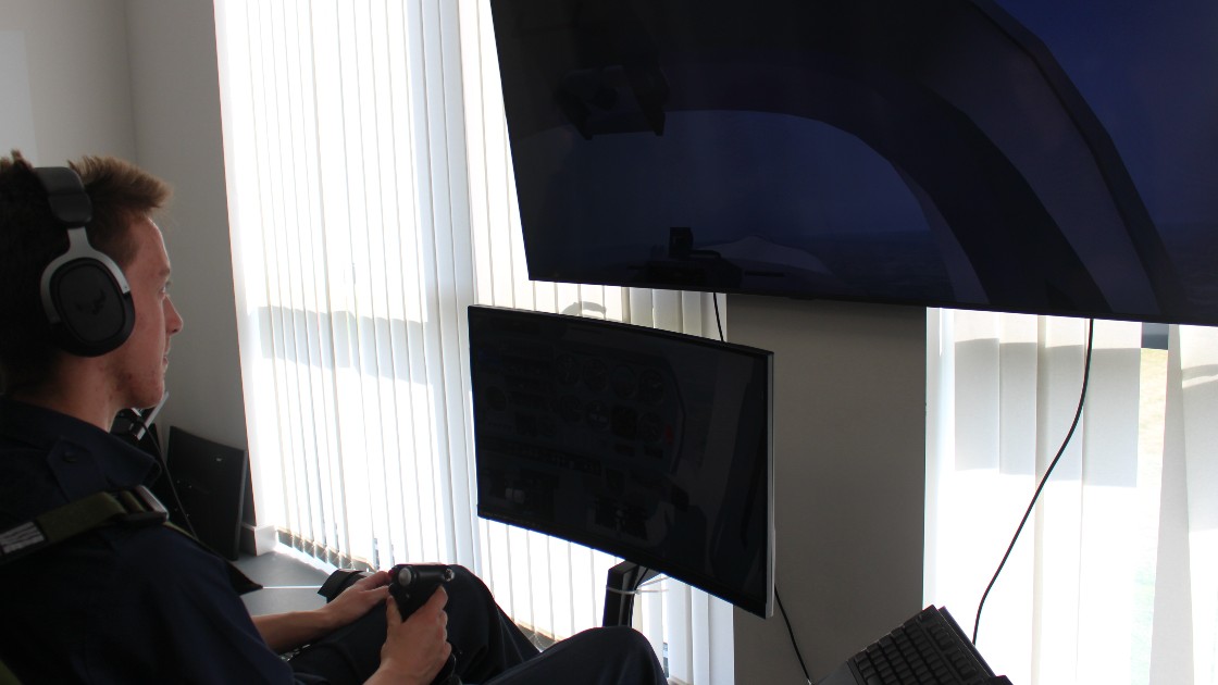 Student using a flight simulator with headphones and joystick