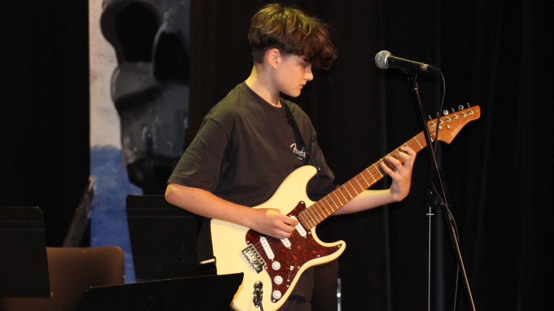 Student playing electric guitar on stage during Summer Fest Day One