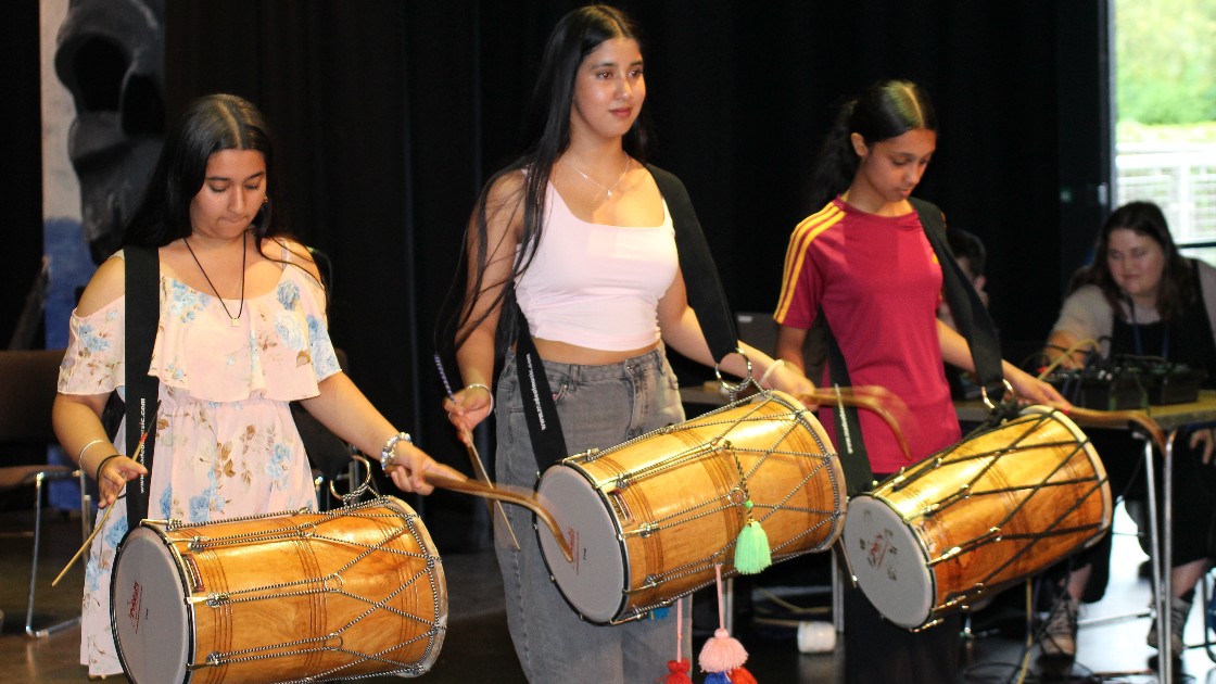 Three students playing traditional drums indoors during Summer Fest Day One