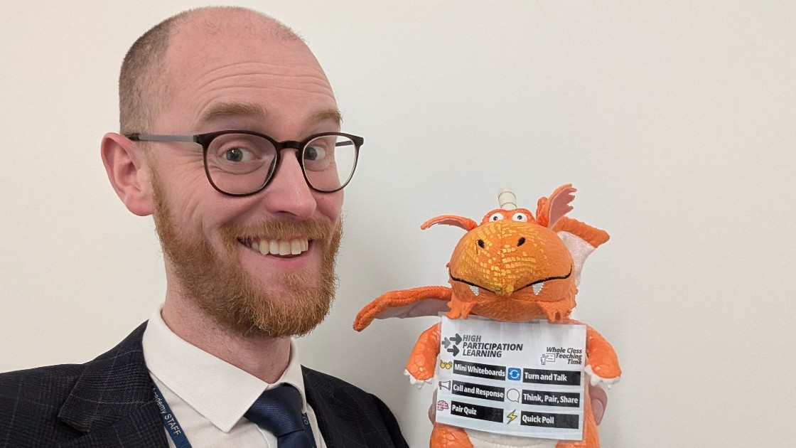 Teacher holding an orange dragon toy with educational labels
