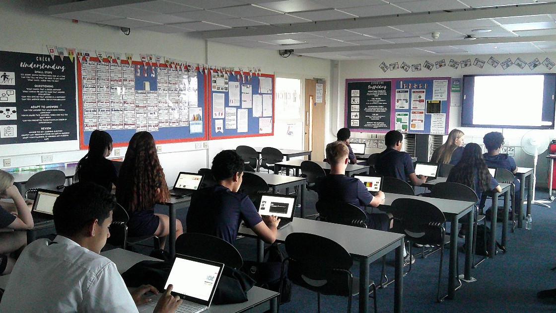 Students in a classroom using laptop to prepare their presentation