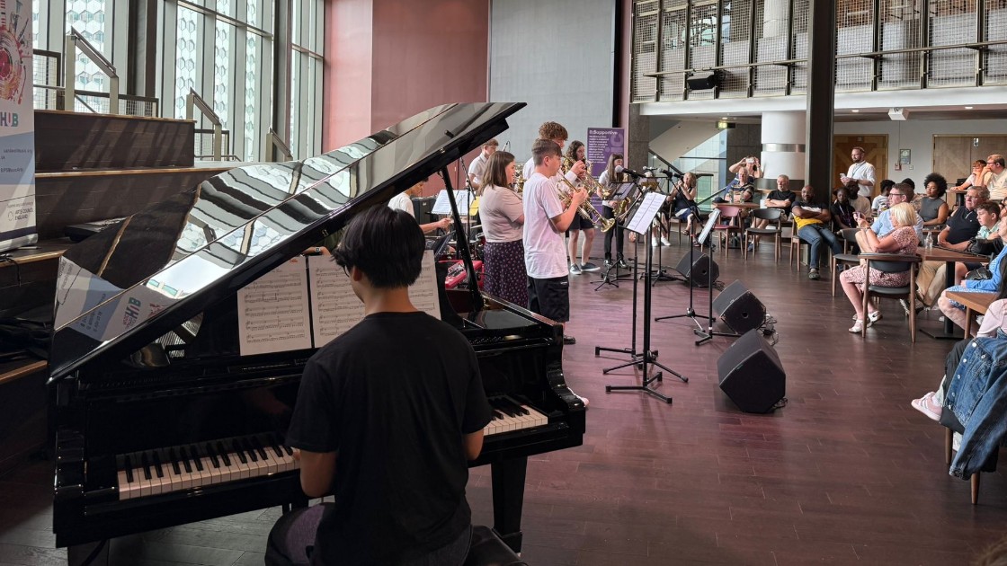 Students performing music with piano and brass instruments in front of an audience