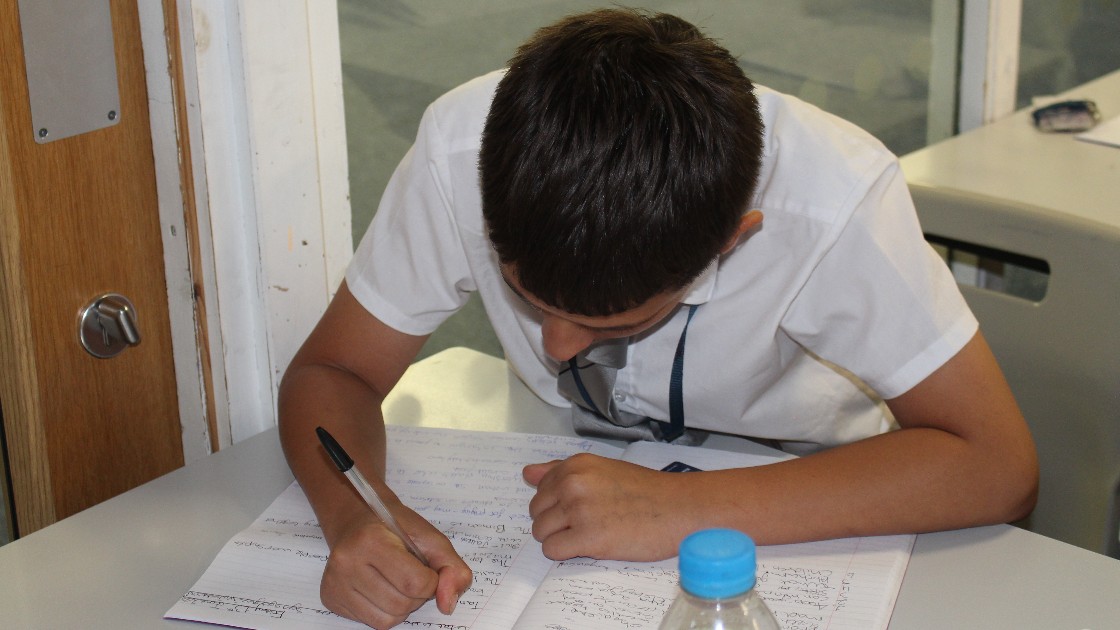 Student writing in an exercise book during a lesson